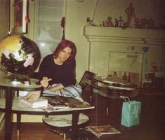 a woman sitting at a table in front of a globe with pictures on the table