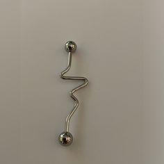 a metal hook with two balls attached to it on a white surface next to a wall