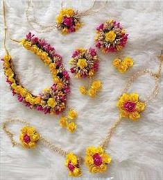 yellow and pink flowers are arranged on a white furnishing with gold chain necklaces