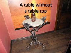 a table with a bottle sitting on top of it next to a pink wall and wooden floor