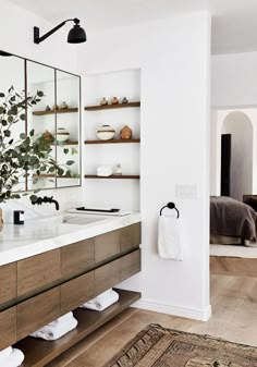 a bathroom with two sinks, mirrors and plants on the counter top in front of it