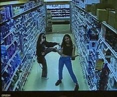 two women are standing in the aisle of a store and one is pointing at something