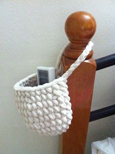 a cell phone in a basket on top of a wooden stand next to a wall