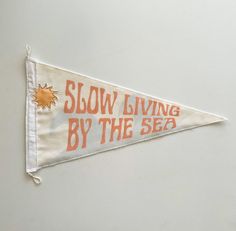 an orange and white banner that says slow living by the sea hanging on a wall