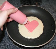 someone is using a pink crayon to decorate a heart in a frying pan