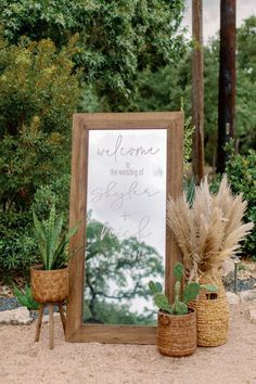 a welcome sign and potted plants in front of a mirror