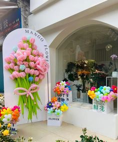 a bunch of flowers that are on display in front of a flower shop with balloons