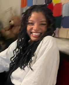 a woman with dreadlocks sitting in front of a teddy bear