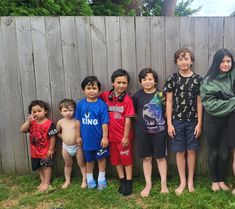 a group of children standing in front of a wooden fence