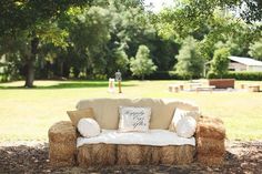 a couch sitting in the middle of a field with hay bales on top of it