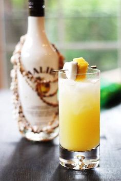 a glass filled with yellow liquid next to a bottle