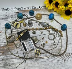 a bunch of jewelry sitting on top of a wooden table next to sunflowers