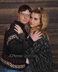 a man and woman hugging each other in front of a wooden wall