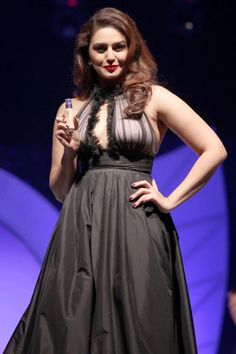 a woman in a black dress is standing on a stage with her hands on her hips