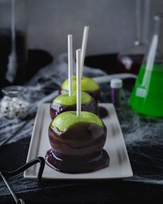 three chocolate covered apples on a plate with toothpicks sticking out of the top