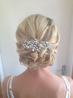 the back of a woman's head wearing a wedding hairstyle with pearls on it