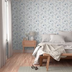 a white bed sitting in a bedroom next to a wooden dresser and window with blue flowers on it