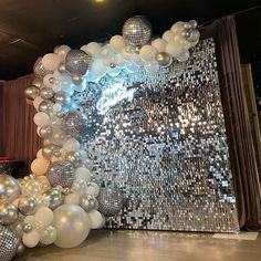 silver and white balloons in front of a disco ball backdrop