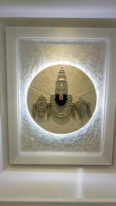 an art piece is displayed in the center of a white frame with light shining on it