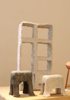 two sculptures made out of cement sitting on top of a table next to a chair