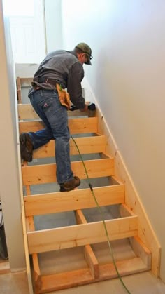 a man is working on some stairs in the house with wood planks around him