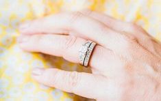 a woman's hand with two wedding bands on her ring and the other half of her finger