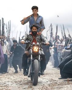 a man riding on the back of a motorcycle next to another man holding a baseball bat