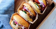 three hot dogs sitting on top of a wooden tray