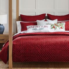 the comforter is red and white with polka dots on it, along with pillows that say comfort & joy