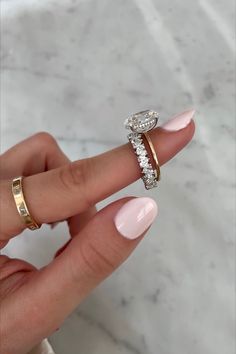 a woman's hand with two gold rings and one diamond ring on her finger