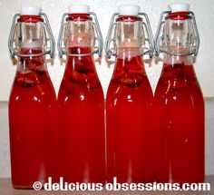 four bottles filled with liquid sitting on top of a counter