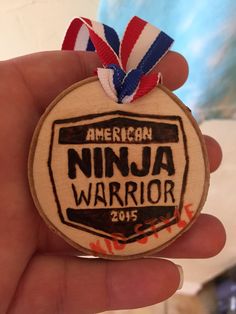 a person holding up a medal for an american ninja warrior contest in their left hand