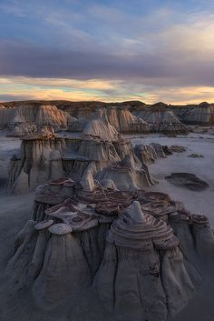 the desert is covered in many different types of rock formations and sand dunes at sunset