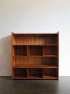 an empty wooden bookcase against a white wall