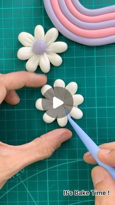 two hands are making flowers out of plastic