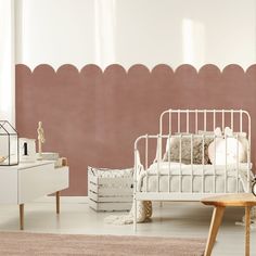 a white bed sitting in a bedroom next to a dresser and table with a clock on it