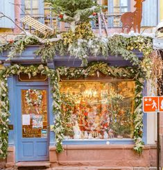 a store front decorated with christmas decorations and greenery