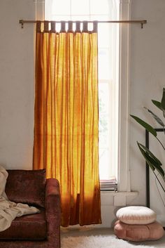 a living room filled with furniture and a window covered in yellow drapes next to a white rug