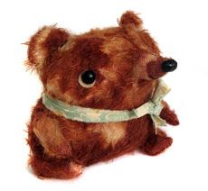 a brown teddy bear with a green ribbon around its neck sitting on a white surface