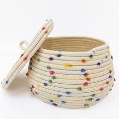 a white basket with multicolored beads and a wooden stick sticking out of it