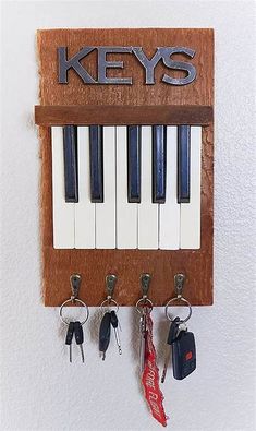 keys are hanging on the wall with key hooks attached to it and there is a key holder made out of wood