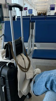 two pieces of luggage sitting on top of a floor next to blue chairs in an airport