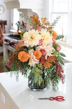 a vase filled with lots of flowers on top of a counter next to a pair of scissors