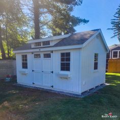 a small white shed sitting in the grass