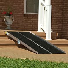 a black ramp sitting on top of a wooden deck next to a flower planter