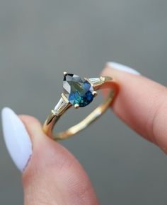 a woman's hand holding an engagement ring with a blue diamond