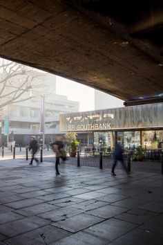 people walking under an overpass on a city street