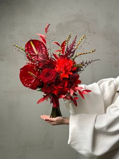 a woman holding a bouquet of red flowers