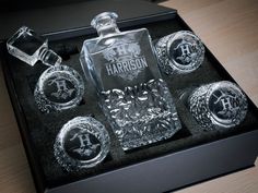 an assortment of personalized glass items in a black box on top of a wooden table