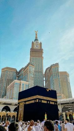 the ka'bah in front of some tall buildings with a clock on it